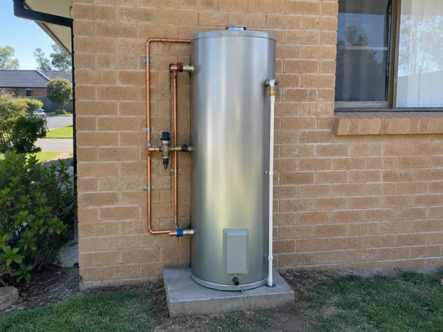 Outdoor hot water cylinder on a brick house wall beside a window and concrete slab in Rouse Hill